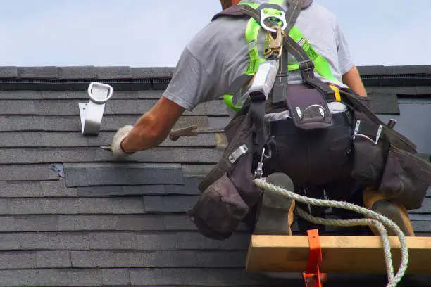 Experienced roofing professional inspecting roof valley damage and flashing with specialized tools
