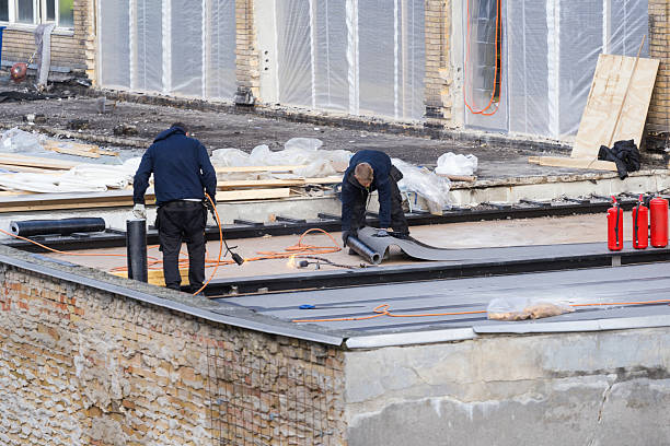 Experienced roofer evaluating worn shingles and flashing for a full replacement recommendation