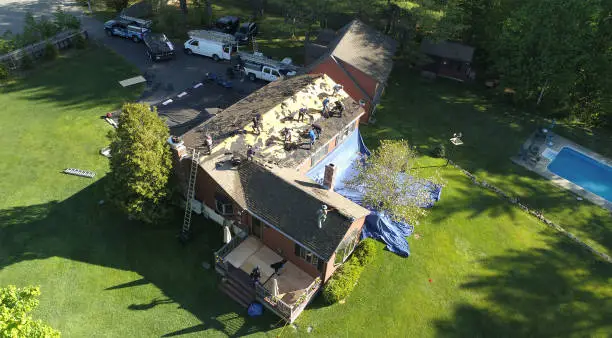 Roofing professional inspecting damaged shingles and flashing before full replacement work