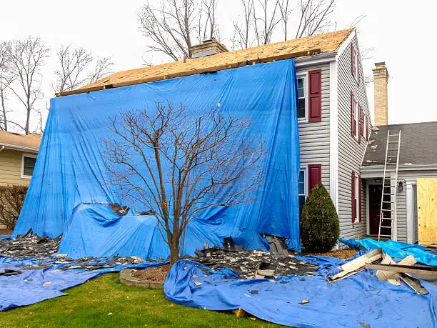 Roof replacement crew installing new shingles on an older Del City home