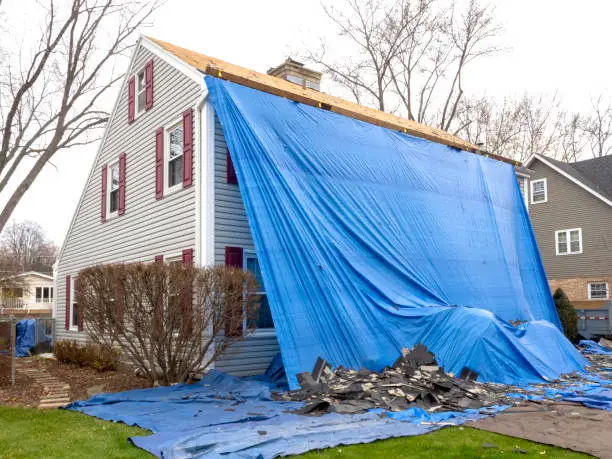 Roofing crew replacing storm-worn shingles on an occupied Lexington home during a planned daytime project